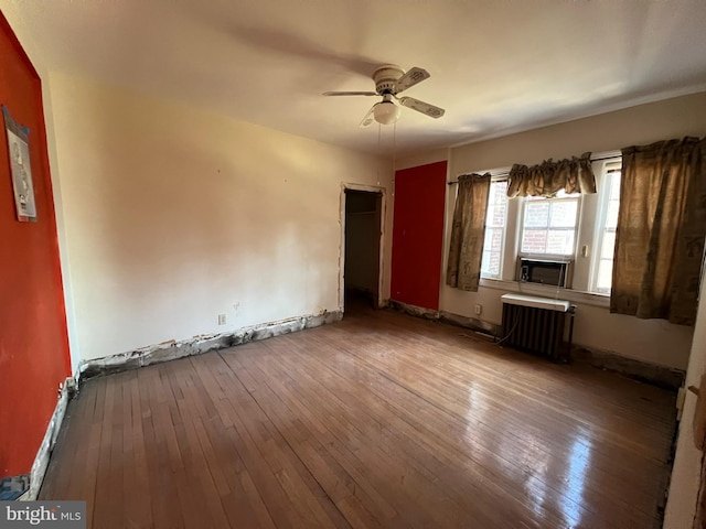 empty room featuring radiator, ceiling fan, cooling unit, and wood-type flooring