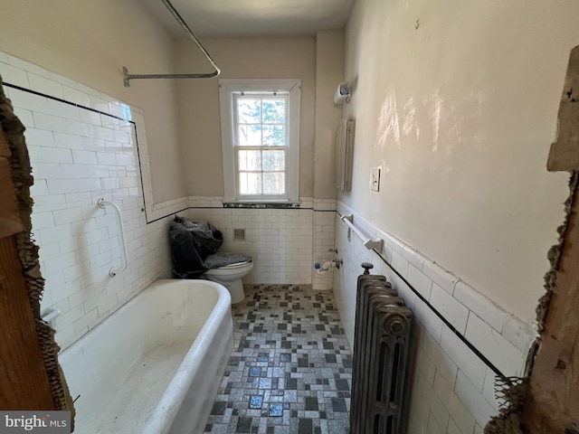 bathroom featuring toilet, radiator heating unit, and tile walls