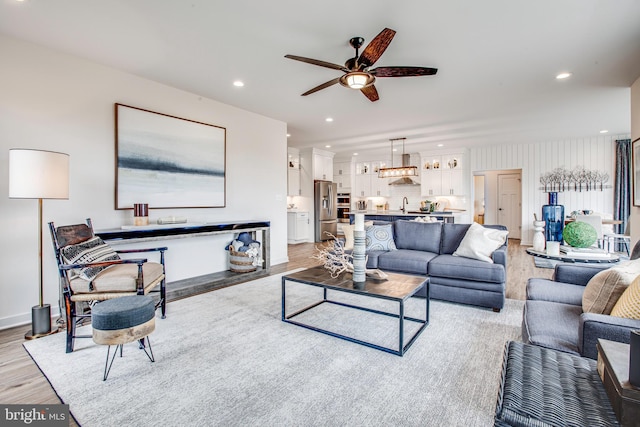 living room featuring ceiling fan, sink, and light wood-type flooring