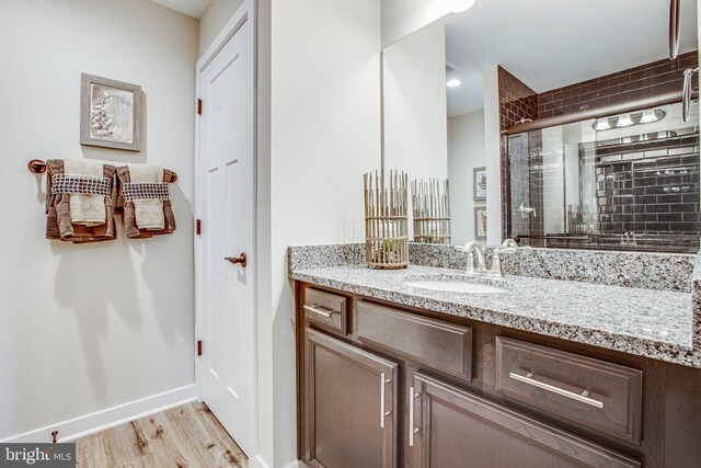 bathroom with hardwood / wood-style floors, vanity, and a shower with door