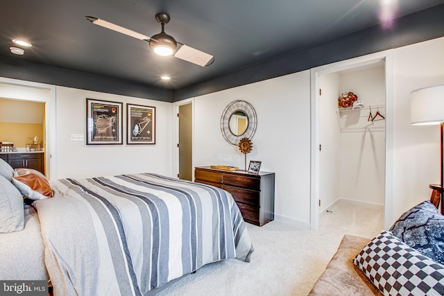 bedroom with ensuite bath, light colored carpet, ceiling fan, a spacious closet, and a closet