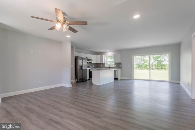 unfurnished living room featuring ceiling fan, wood-type flooring, and sink