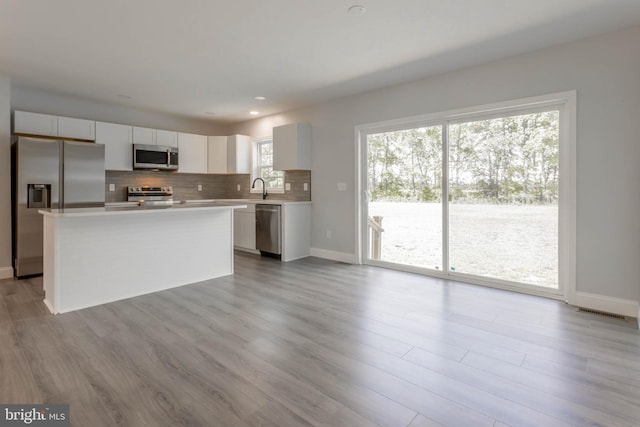 kitchen featuring white cabinets, appliances with stainless steel finishes, a center island, and a wealth of natural light