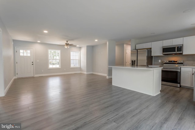 kitchen featuring white cabinetry, ceiling fan, stainless steel appliances, a kitchen island, and light wood-type flooring