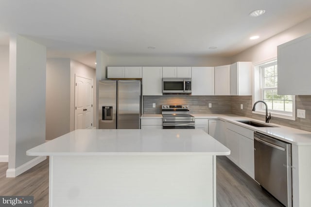 kitchen with white cabinets, sink, light hardwood / wood-style flooring, appliances with stainless steel finishes, and a kitchen island