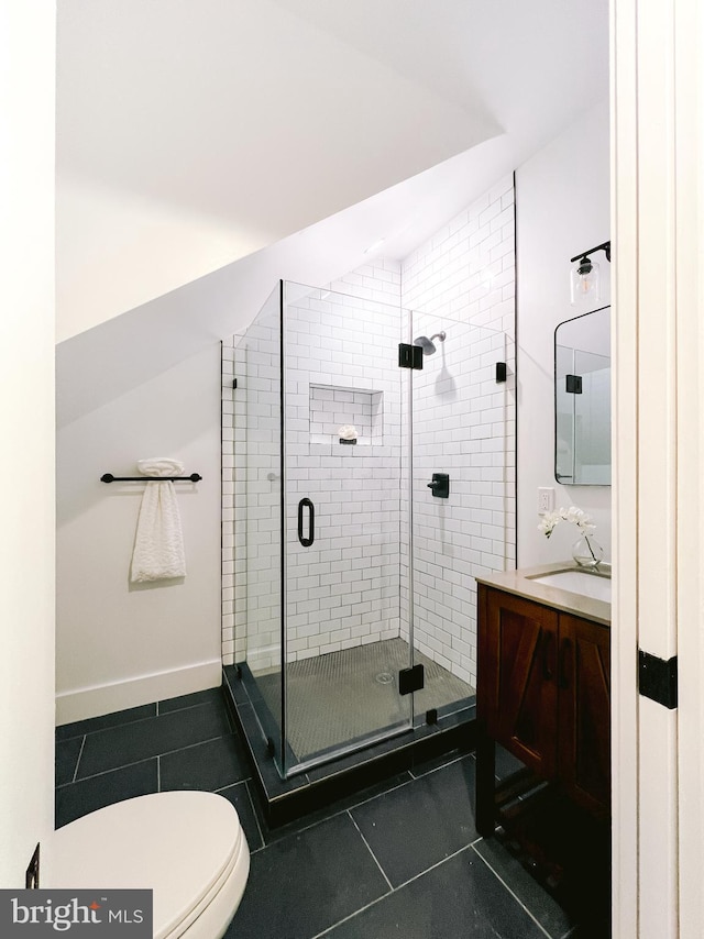 bathroom featuring tile patterned floors, vanity, a shower with shower door, and toilet