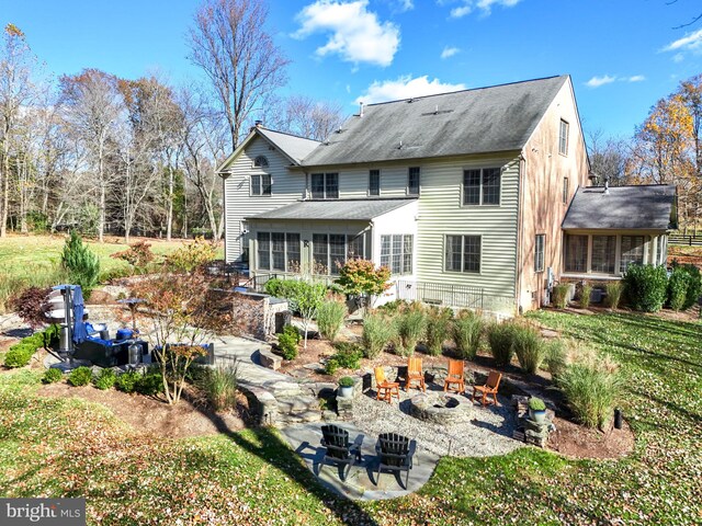 rear view of property with a yard, a patio, and a fire pit