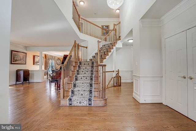 stairs with hardwood / wood-style flooring, ornamental molding, and a towering ceiling