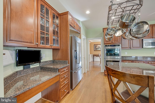 kitchen featuring pendant lighting, light hardwood / wood-style flooring, dark stone counters, and appliances with stainless steel finishes