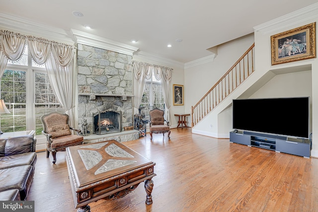 living room with hardwood / wood-style floors, a stone fireplace, and crown molding