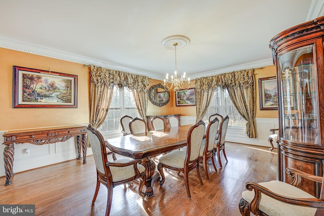 dining space with light hardwood / wood-style floors, an inviting chandelier, and crown molding