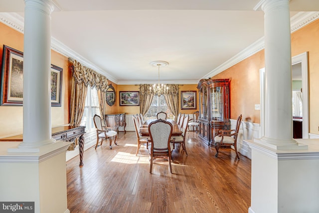 dining area with hardwood / wood-style flooring, a notable chandelier, ornate columns, and crown molding