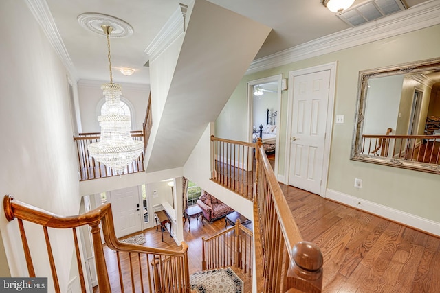 staircase featuring wood-type flooring, crown molding, and a chandelier