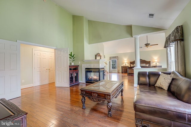 living room featuring hardwood / wood-style flooring, ceiling fan, a multi sided fireplace, and high vaulted ceiling