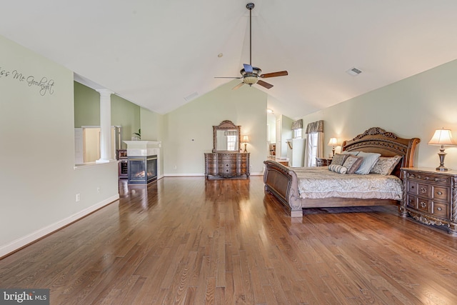 bedroom featuring ceiling fan, a multi sided fireplace, wood-type flooring, and lofted ceiling