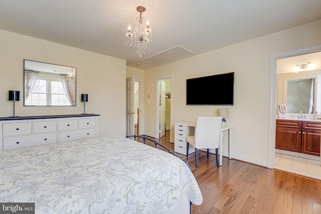 bedroom featuring connected bathroom, light hardwood / wood-style floors, a notable chandelier, and sink