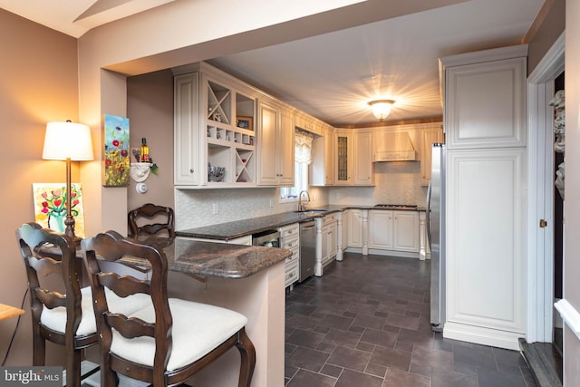 kitchen featuring kitchen peninsula, appliances with stainless steel finishes, backsplash, and sink