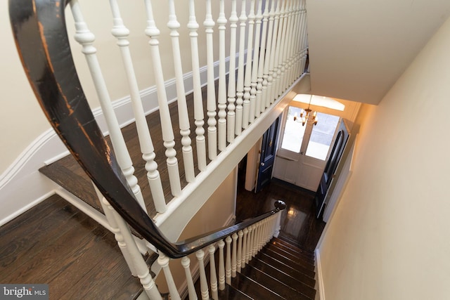 staircase featuring hardwood / wood-style floors and an inviting chandelier