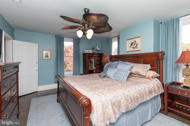 bedroom with ceiling fan, dark hardwood / wood-style flooring, and multiple windows