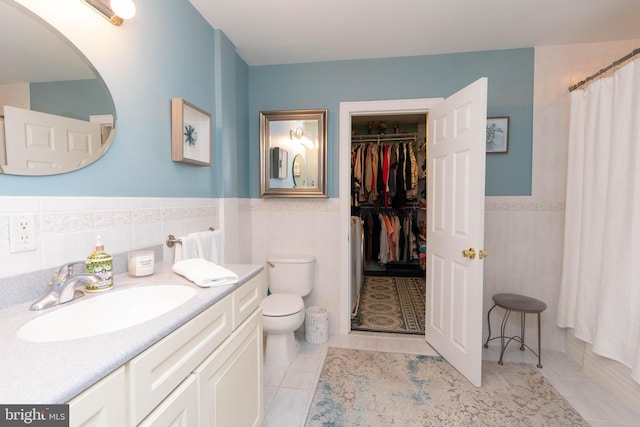 bathroom featuring tile patterned flooring, vanity, toilet, and tile walls