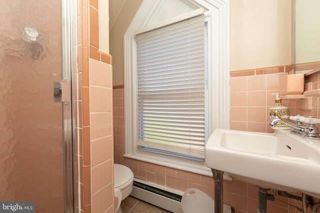 bathroom featuring toilet, tile walls, a baseboard heating unit, and sink