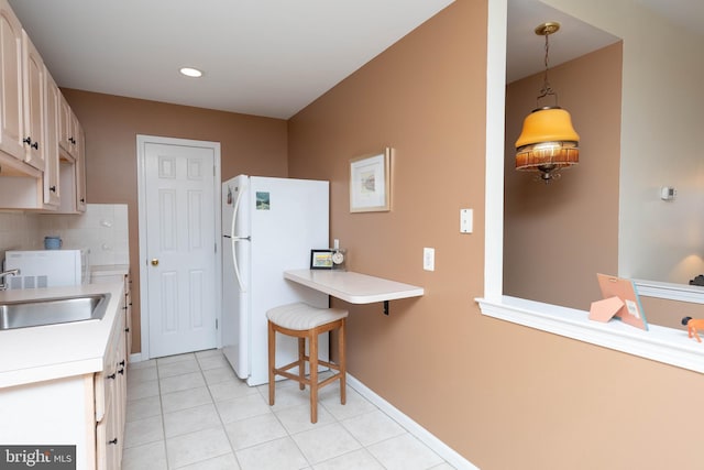 kitchen featuring backsplash, a breakfast bar, sink, pendant lighting, and white fridge