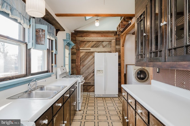 kitchen with sink, wood walls, white appliances, washer / dryer, and dark brown cabinets