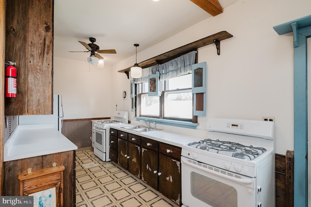 kitchen with white range, hanging light fixtures, sink, dark brown cabinets, and white range with gas cooktop