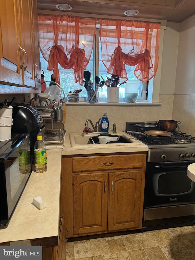 533 Hamilton St, Lancaster, PA 17602 - kitchen featuring gas stove, light countertops, a sink, brown cabinetry, and light stone finish flooring