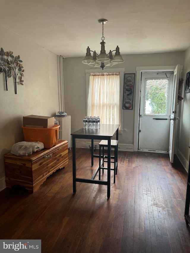 dining area with dark hardwood / wood-style flooring, radiator heating unit, and an inviting chandelier