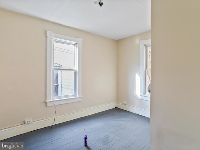 empty room with dark hardwood / wood-style flooring and plenty of natural light