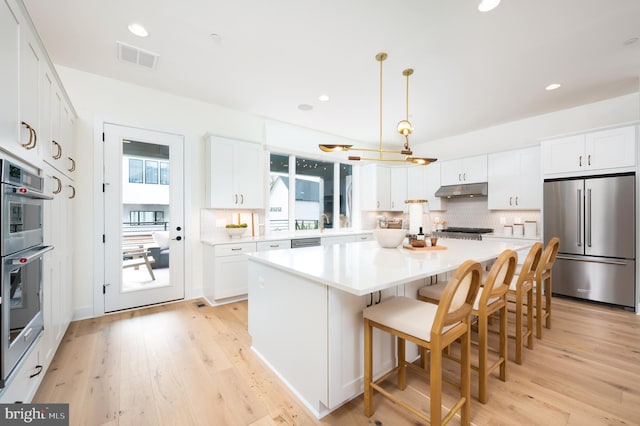 kitchen with pendant lighting, a kitchen island, white cabinetry, and appliances with stainless steel finishes