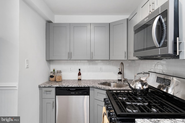 kitchen featuring backsplash, gray cabinetry, sink, and stainless steel appliances