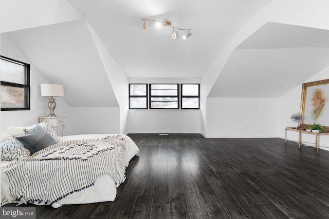 bedroom featuring track lighting, dark wood-type flooring, and vaulted ceiling