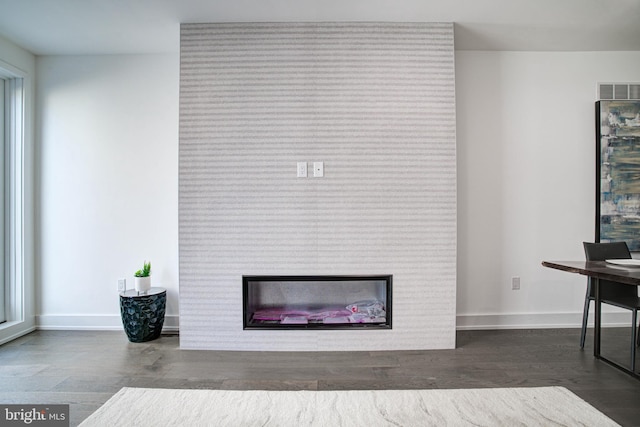 interior space featuring dark hardwood / wood-style flooring and a large fireplace