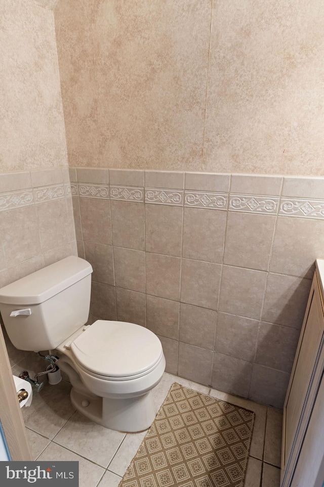 bathroom featuring tile patterned flooring, vanity, toilet, and tile walls