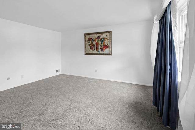 empty room featuring a healthy amount of sunlight and dark colored carpet