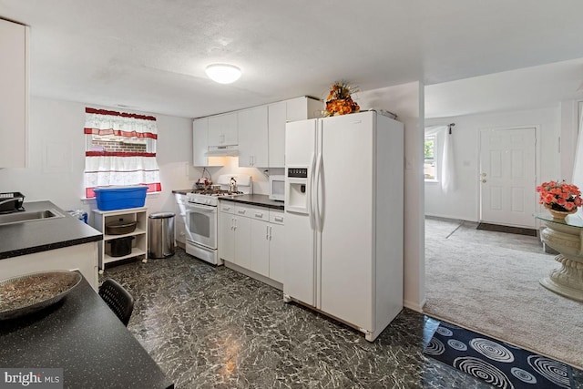 kitchen with sink, white cabinets, dark carpet, and white appliances