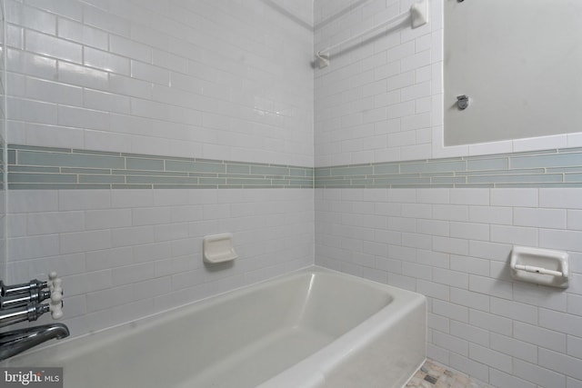 bathroom with tiled shower / bath combo and tile walls