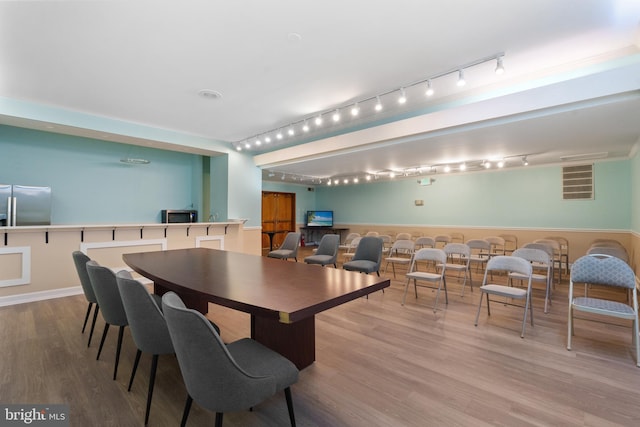 dining room with hardwood / wood-style flooring and track lighting