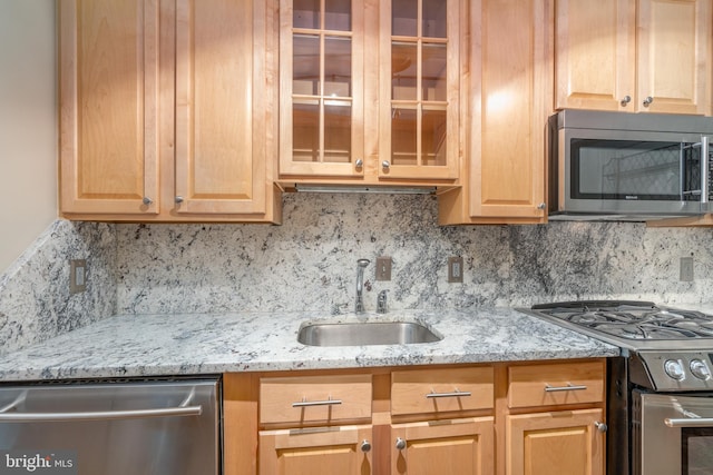 kitchen with backsplash, light stone counters, sink, and stainless steel appliances