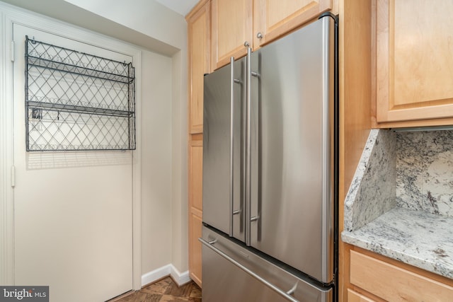 kitchen featuring high end refrigerator, light brown cabinets, and light stone counters