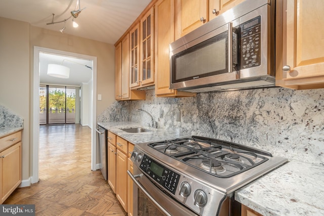 kitchen featuring backsplash, light stone counters, sink, and stainless steel appliances