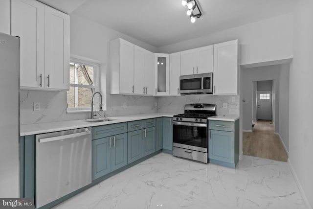 kitchen featuring white cabinetry, sink, blue cabinets, decorative backsplash, and appliances with stainless steel finishes