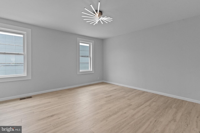 unfurnished room featuring light wood-type flooring and a chandelier