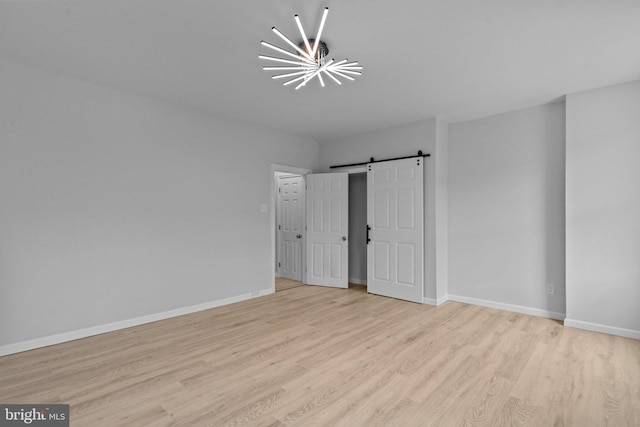 unfurnished bedroom with a barn door and light wood-type flooring