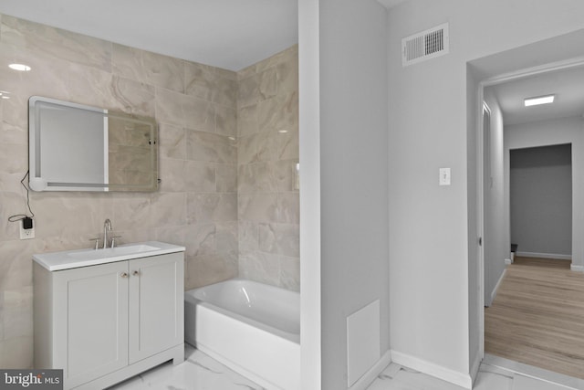 bathroom featuring vanity, wood-type flooring, tile walls, and bathtub / shower combination