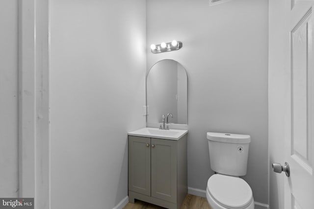 bathroom with hardwood / wood-style floors, vanity, and toilet