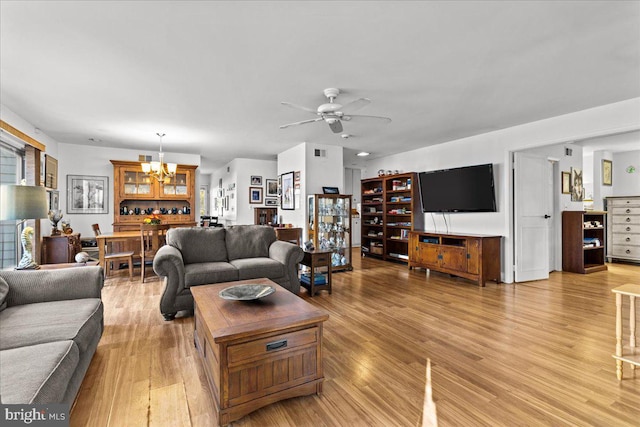 living room featuring light hardwood / wood-style flooring, a healthy amount of sunlight, and ceiling fan with notable chandelier