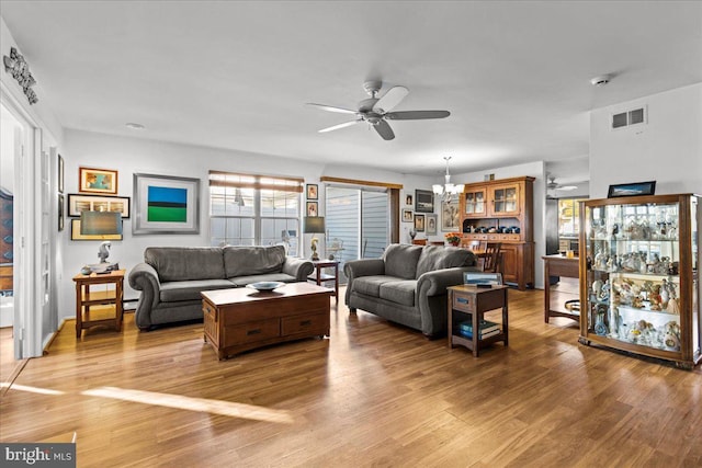 living room with ceiling fan with notable chandelier and light wood-type flooring